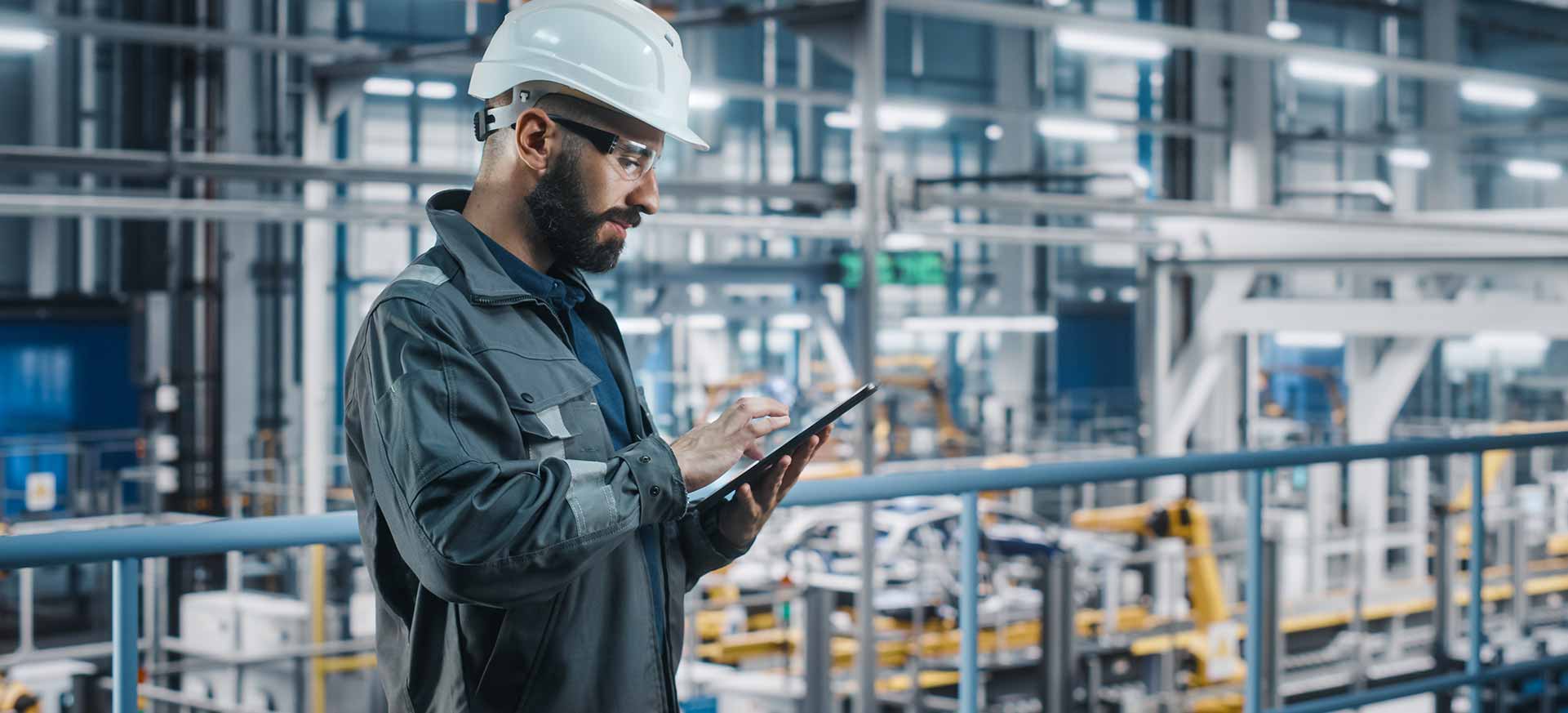 Werker vor Fabrik mit Tablet um aufbereitete Daten zu überprüfen